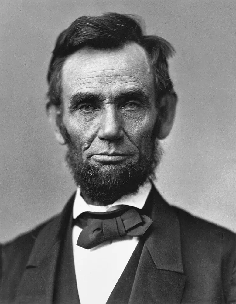 Black-and-white studio portrait of a bearded man with dark hair, wearing a bow tie and dark suit