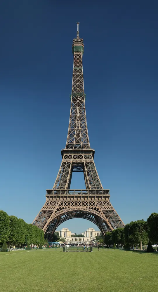 A tall iron lattice tower rising above a wide green lawn under a deep blue sky
